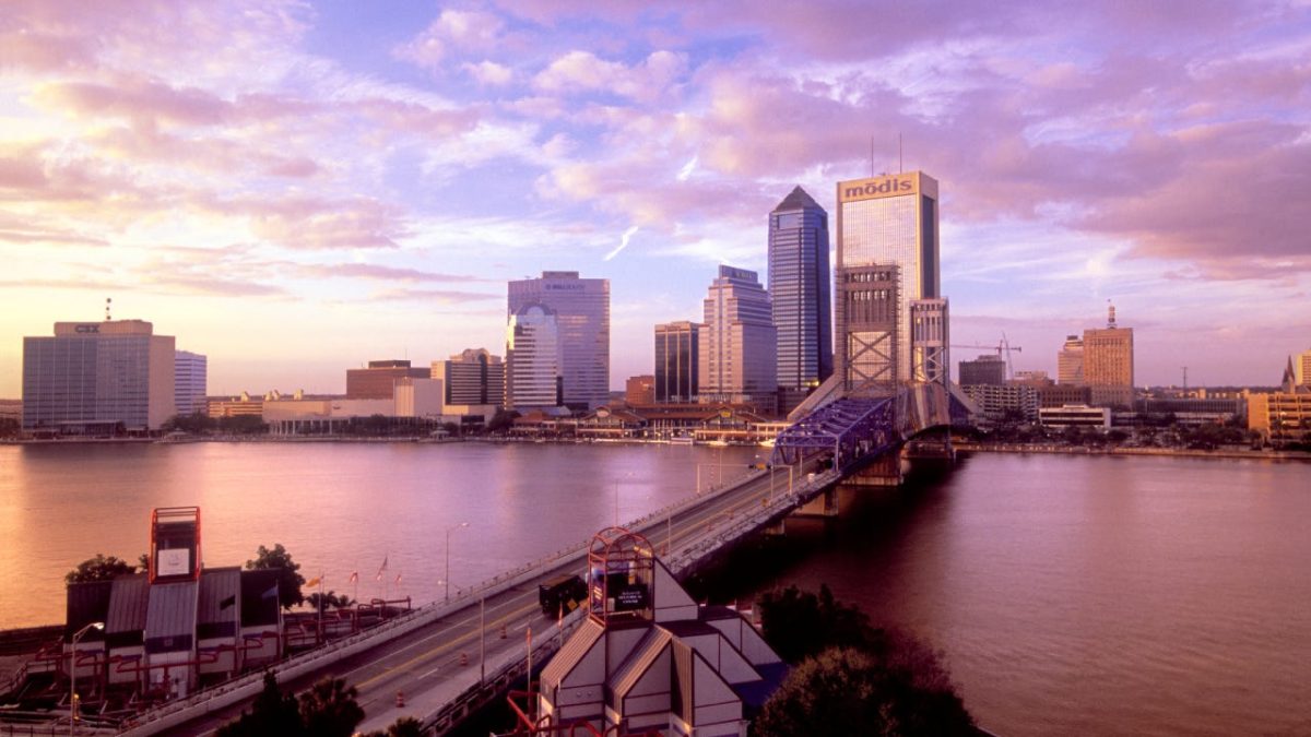 Skyline of Jacksonville, Florida with the sky turning purple and the sun setting.