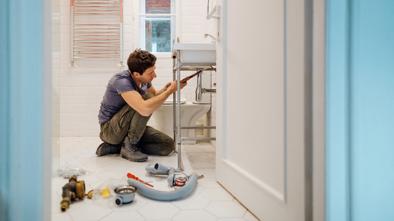 man working on plumbing in home